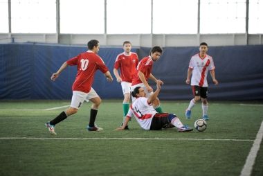 People playing soccer on an artificial indoor turf.